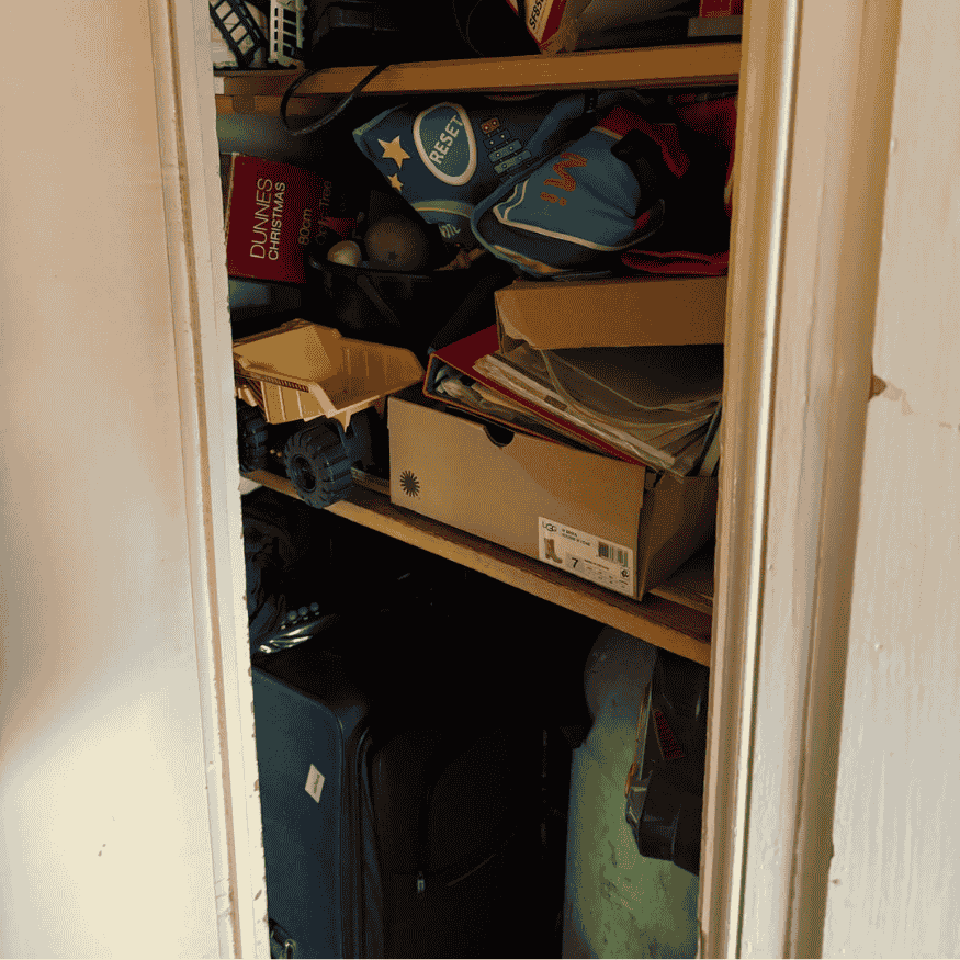 Cluttered storage cupboard before landlord property refurbishment in Northampton, filled with boxes, toys, and disorganised items.