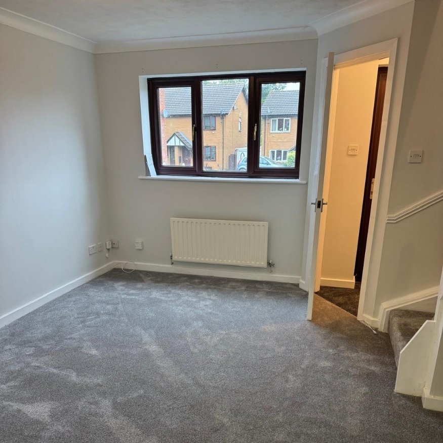 Living area rejuvenated with soft grey carpet, clean skirting boards, and a complete repaint—ideal for new tenants or buyers.