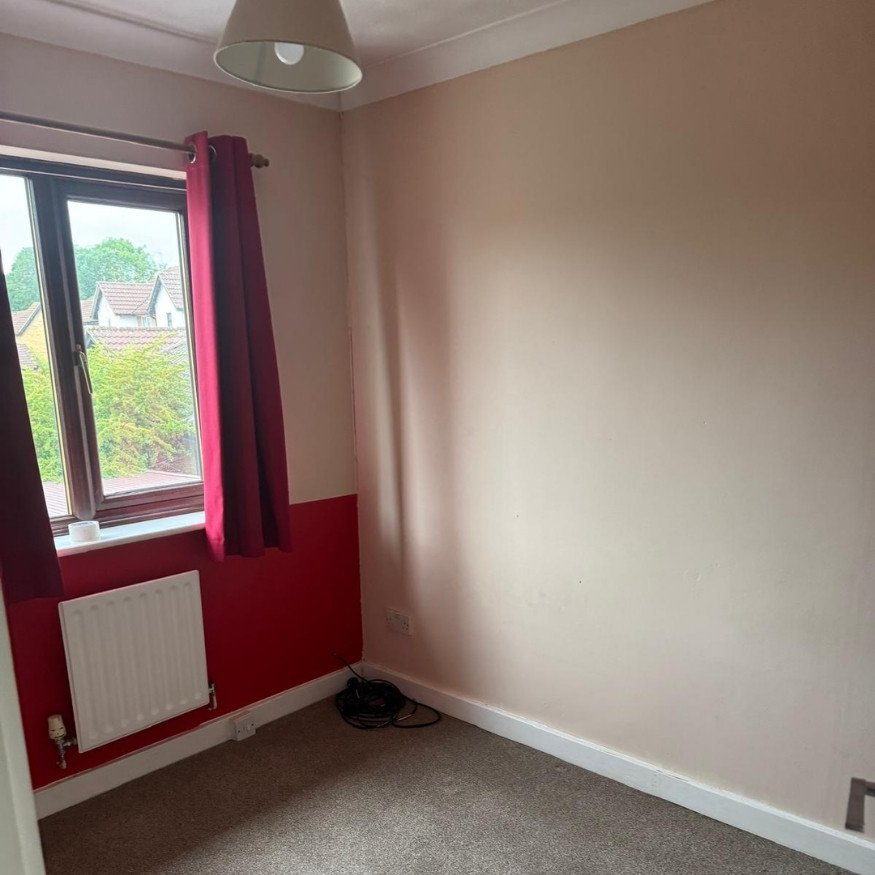 Back bedroom with inconsistent wall paint
Red feature walls and partially faded paint created a mismatched, outdated room feel.