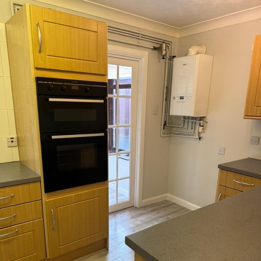 Appliance wall freshly detailed as part of full property refurbishment in Wellingborough with new paint, laminate cleaning, and pipe work presentation for a neat, finished look.