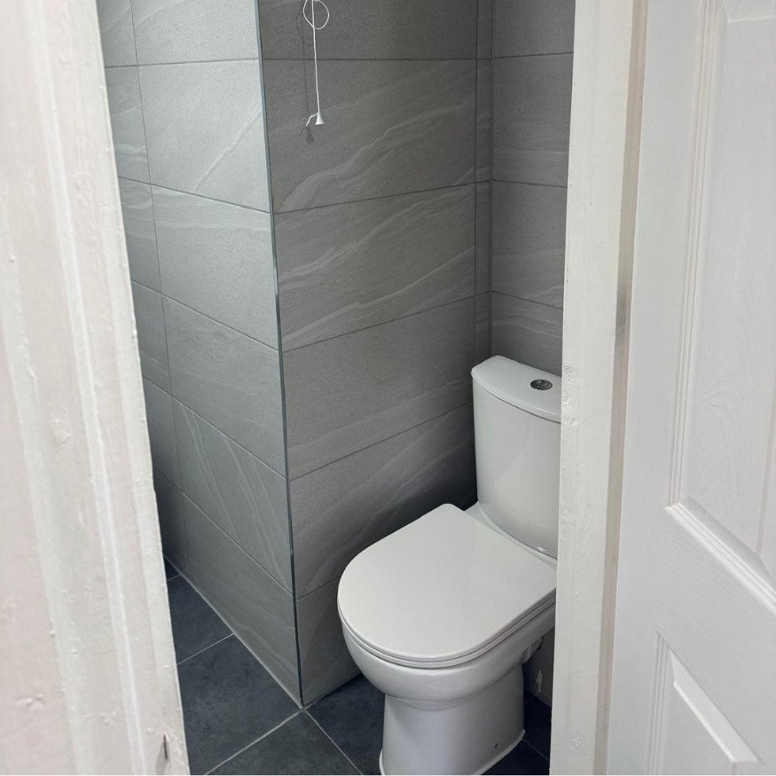 Refurbished bathroom with new sanitaryware, modern tiles, and upgraded shower unit.