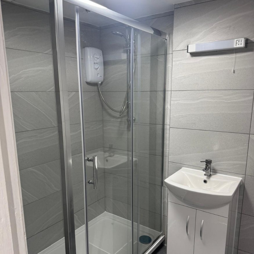 Refurbished bathroom with new sanitaryware, modern tiles, and upgraded shower unit.