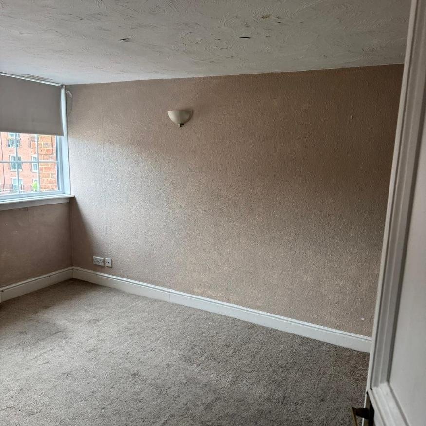 Initial condition of the living room before the property renovation in Northamptonshire, showing worn carpets and aged décor.