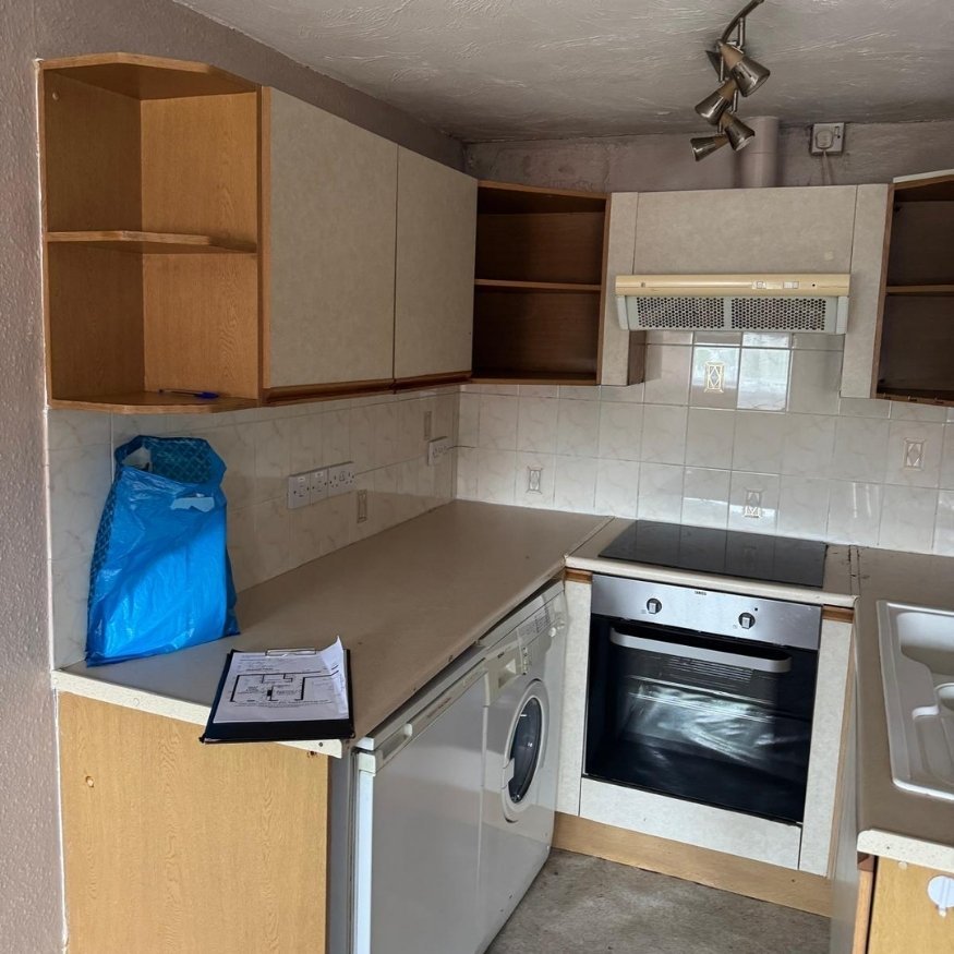 Dated kitchen area with stained surfaces and old units in need of modernisation.