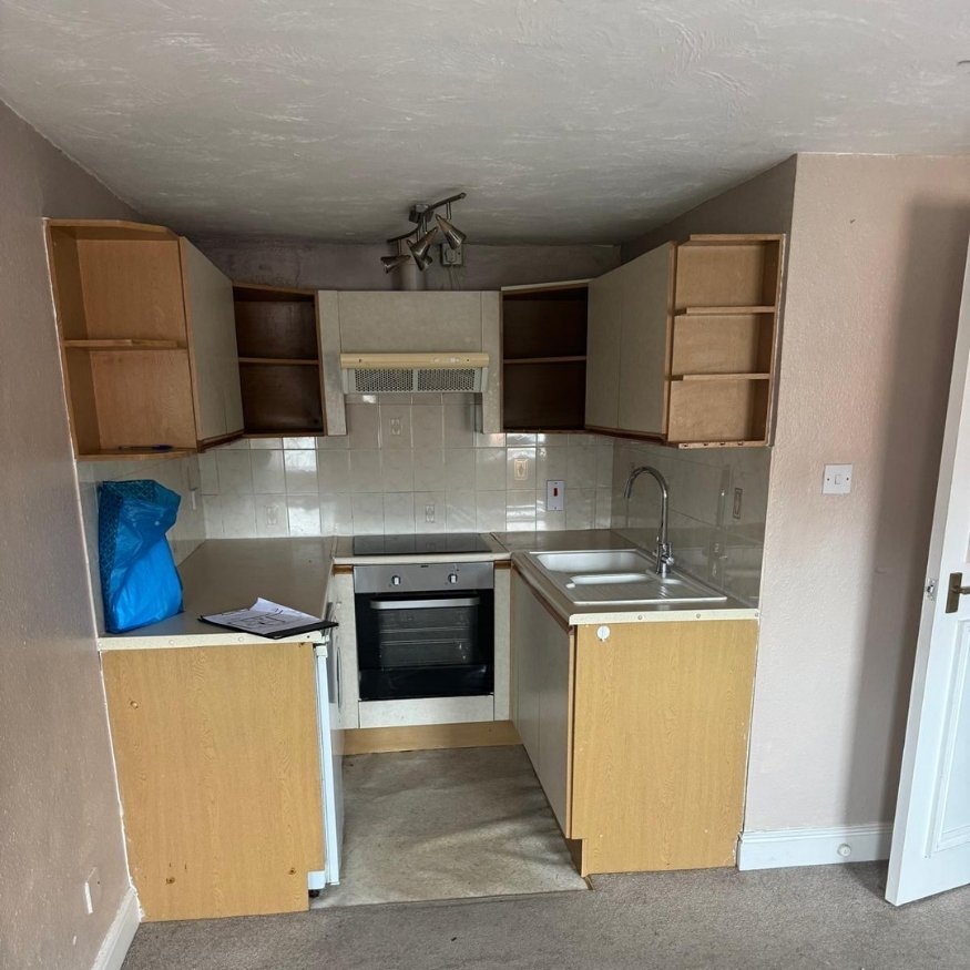 Dated kitchen area with stained surfaces and old units in need of modernisation.